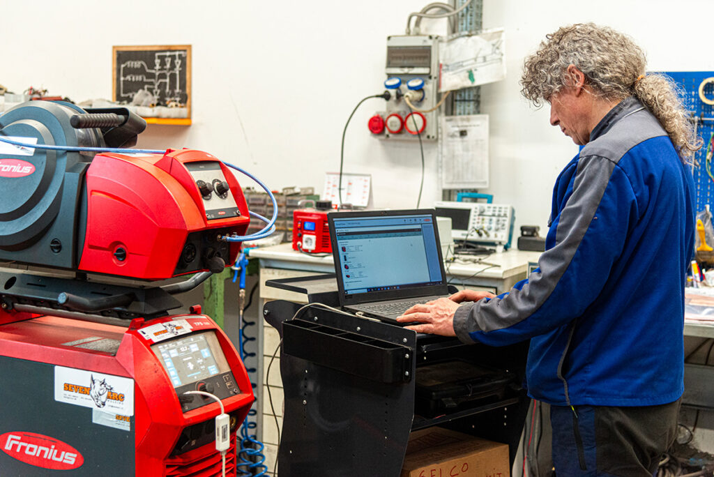 Tecnico Seven Arc Building utilizza laptop per configurare apparecchiature industriali.